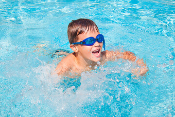 Happy boy in a swimming pool. Cute little kid boy having fun in a swimming pool. Outdoors. Sport activities for children.