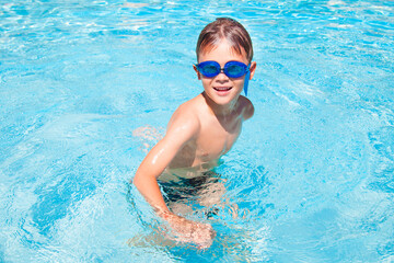 Fototapeta na wymiar Happy boy in a swimming pool. Cute little kid boy having fun in a swimming pool. Outdoors. Sport activities for children.