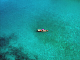 A lonely boat is floating peacefully in the middle of a vast blue ocean, aerial view