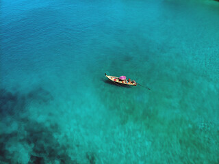 Fototapeta premium A lonely boat is floating peacefully in the middle of a vast blue ocean, aerial view