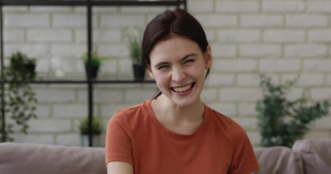 Overjoyed positive millennial pretty caucasian girl laughing at funny joke, feeling excited enjoying pleasant online distant conversation with friends at home, head shot close up web camera view.