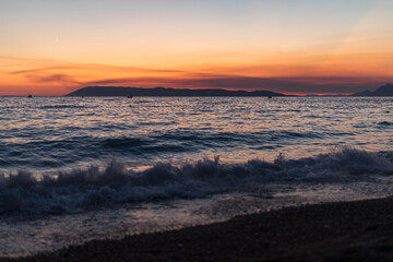 Sonnenuntergang an der Küste in Tučepi in Kroatien. Blick auf das Meer, die Wellen, die Insel Brač und die Berge