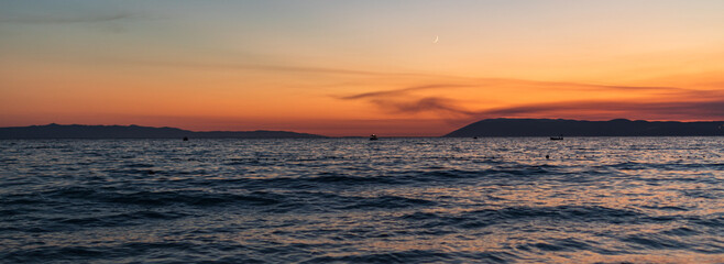 Sonnenuntergang an der Küste in Tučepi in Kroatien. Blick auf das Meer, die Wellen, die Insel Brač und die Berge
