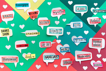 Thank You in many languages. Paper art, creative flat lay, top view on paper tags. International Thank you day. Creative background on colored layered geometric paper background.