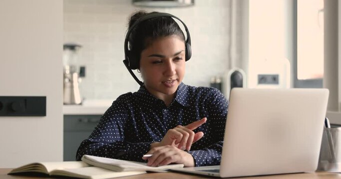 Focused motivated young indian ethnicity female student taking professional consultation online from tutor, using videocall computer application, discussing educational project or checking homework.