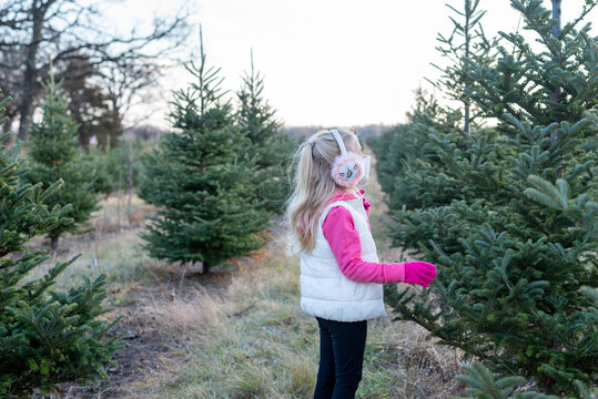 Little Girl In Ear Muffs And Face Mask At The Christmas Tree Farm