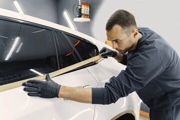 Auto body repair series. Masking car before repaint. Man in a black uniform.