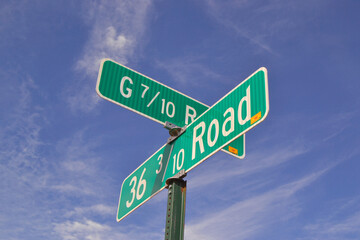 Unusual road directional signs with fractions close-up at a crossroad, with a blue sky background.