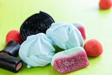 Group of colorful italian sweets for party: black licorice candies on a green background soft focus photo.