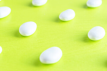 Soft selective focus photo of white glazed almond italian candies for bonbonnieres on light green background.