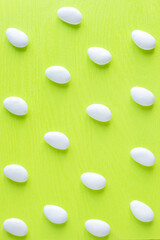 White glazed almond italian candies for bonbonnieres repeating pattern photo on light green background.