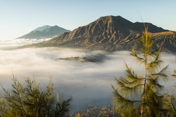 Sunrise view of mount Batur volcano in Bali from Pinggan village. Beautiful sunrise and low clouds. Panoramic view. - 395862564