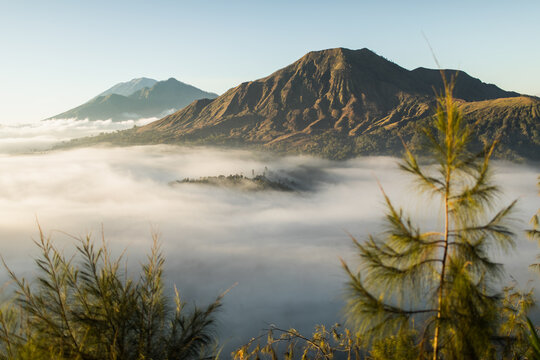 Sunrise view of mount Batur volcano in Bali from Pinggan village. Beautiful sunrise and low clouds. Panoramic view.