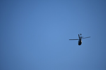 A helicopter flies overhead in Philadelphia in a blue sky.