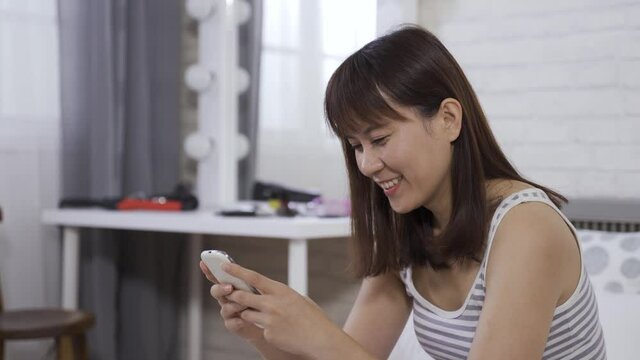 portrait Chinese teenage girl chuckling, having fun playing the mobile games at home. technology and indoor recreation.