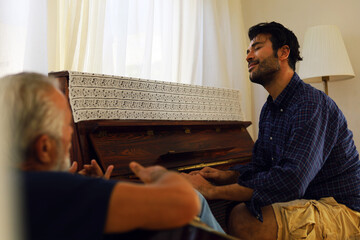 Family time father and son enjoy acoutic guitar and piano at home in holiday weekend.