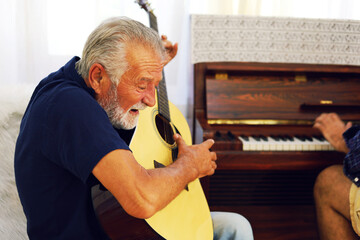 Family time father and son enjoy acoutic guitar and piano at home in holiday weekend.