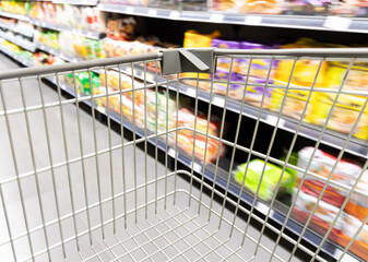 Shopping trolley cart moving in supermarket with motion blur aisle background