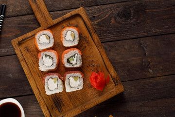 Fototapeta na wymiar Appetizing rolls on a wooden background. Japanese food concept. Close-up. Copy space. Flat lay.
