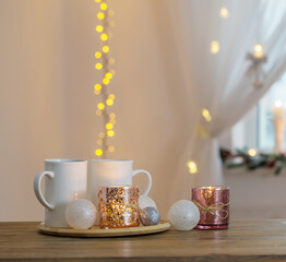 two white cups with christmas decorations on background window