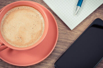 Smartphone, coffee with milk and notepad for notes. Work or relaxation with mobile phone