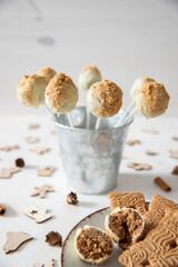 Kuchen am Stiel mit einer Füllung aus Spekulatius und Mascarpone umhüllt mit weißer Schokolade auf einem weißen Tisch aus Holz im Winter zu Weihnachten