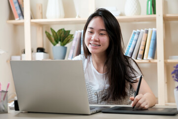 Young girl student studying at home library, using laptop computer, online school concepts,
