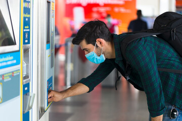 Caucasian man is making a transaction at an automated kiosk to purchase public transport tickets.