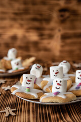 Plätzchen mit Marshmallows, Zuckerguss und Schokolinsen die aussehen wie geschmolzene Schneemänner auf Tellern zur Weihnachtszeit