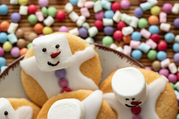 Fototapeta premium Plätzchen mit Marshmallows, Zuckerguss und Schokolinsen die aussehen wie geschmolzene Schneemänner auf Tellern zur Weihnachtszeit