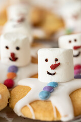 Obraz na płótnie Canvas Plätzchen mit Marshmallows, Zuckerguss und Schokolinsen die aussehen wie geschmolzene Schneemänner auf Tellern zur Weihnachtszeit