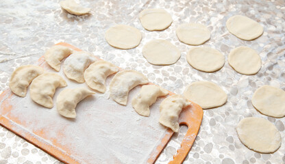 Modeling dumplings from dough on the table.