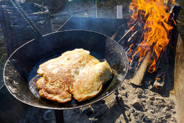 The dough is fried in oil in a pan.