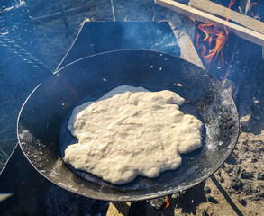 The dough is fried in oil in a pan.