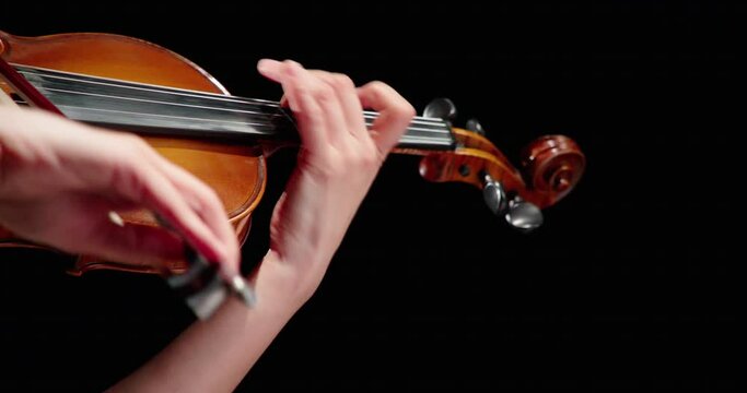 Close-up of a professional violinist playing the violin, a female musician playing the violin, on a black background, 4k video