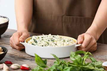 Woman cooking rice casserole on table, closeup