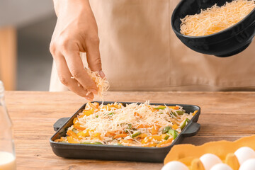 Woman cooking rice casserole on table, closeup