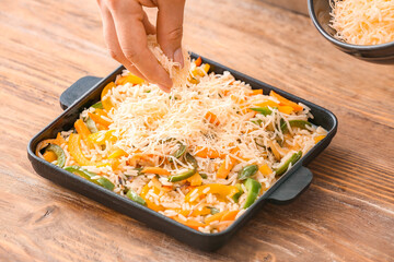 Woman cooking rice casserole on table, closeup