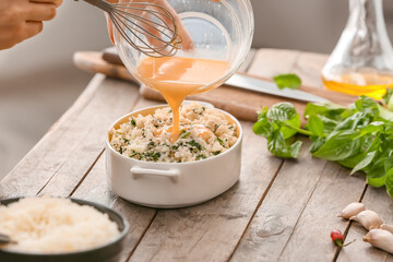 Woman cooking rice casserole on table, closeup