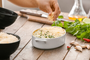 Woman cooking rice casserole on table, closeup