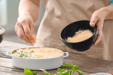Woman cooking rice casserole on table, closeup