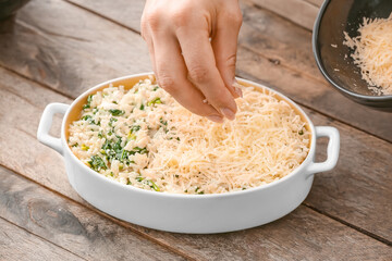 Woman cooking rice casserole on table, closeup
