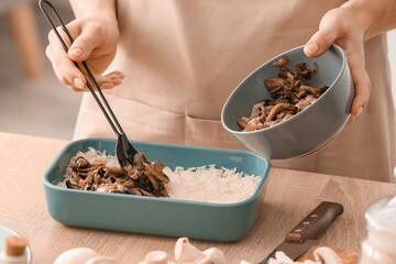 Woman cooking rice casserole on table, closeup