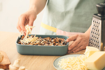 Woman cooking rice casserole on table, closeup