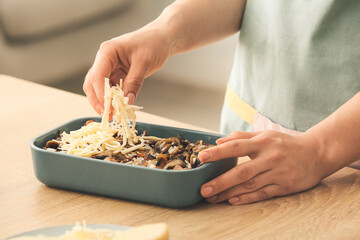 Woman cooking rice casserole on table, closeup