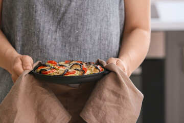 Woman with tasty rice casserole in kitchen, closeup