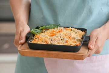 Woman with tasty rice casserole in kitchen, closeup