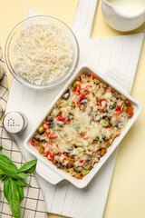 Baking dish with tasty rice casserole on color background
