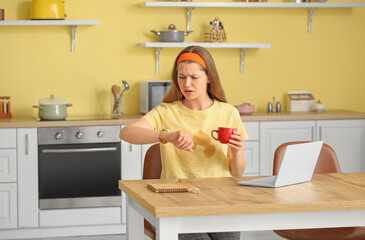 Stressed young woman with coffee stains on her t-shirt in kitchen