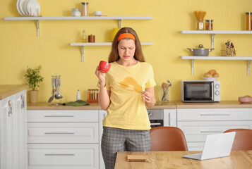 Stressed young woman with coffee stains on her t-shirt in kitchen